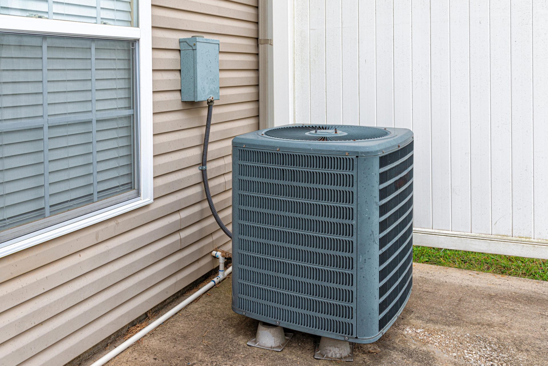 Residential air conditioning condenser on a concrete slab beside a home