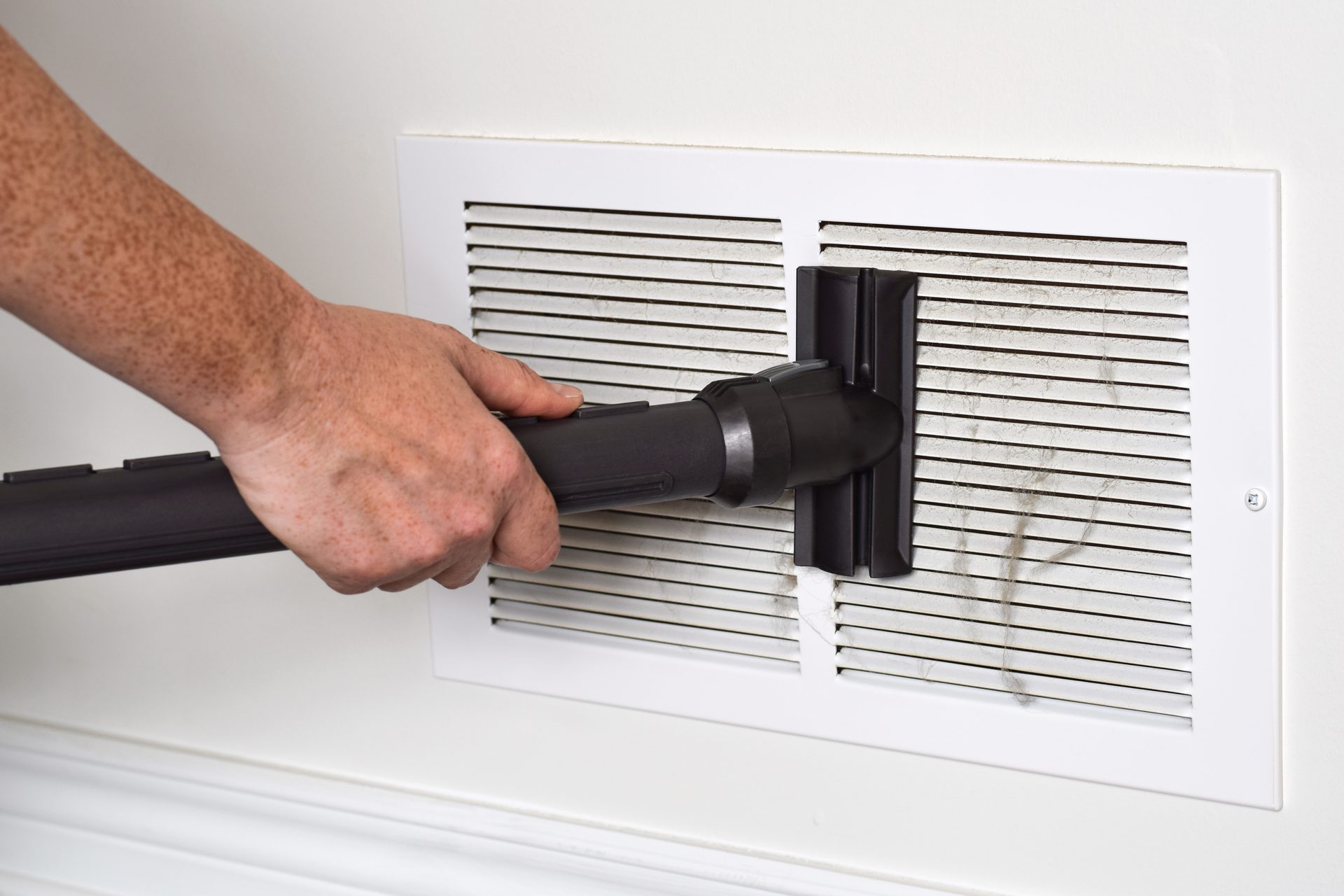 Air conditioning vent being cleaned with a vacuum inside a home